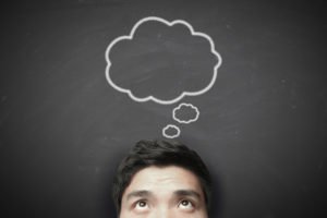 Thinking man with thinking bubble on blackboard background.